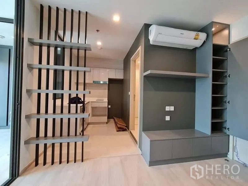 公寓 出售 - 开放式区域设有栅格隔断，白色紧凑厨房，内置橱柜与壁挂空调。