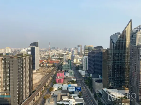 Condominium for rent in Ratchathewi, Bangkok - High-floor Bangkok skyline with rail line and glass office towers under a clear sky.