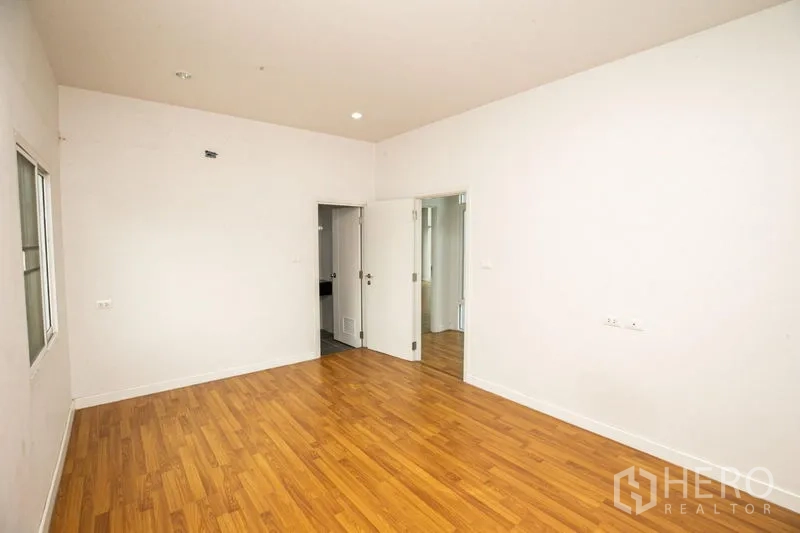 บ้าน ให้เช่าหรือขายในLam Luk Ka, Pathum Thani - ห้องนอนพื้นไม้ ผนังสีขาว พร้อมประตูเข้าส่วนห้องน้ำ