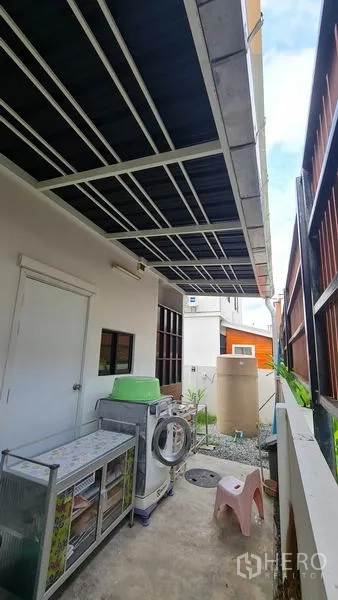 独立式住宅 出售在Samut Prakan - 房屋侧边带顶棚的杂物/洗衣区，设洗衣机与收纳。