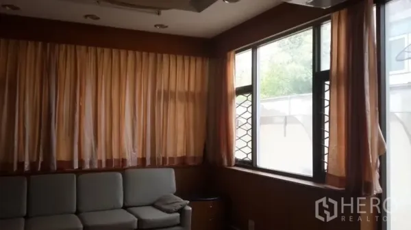 บ้าน ให้เช่าหรือขายในHuai Khwang, Bangkok - ห้องนั่งเล่นอบอุ่น โซฟา L พร้อมผ้าม่านยาวและผนังลายไม้