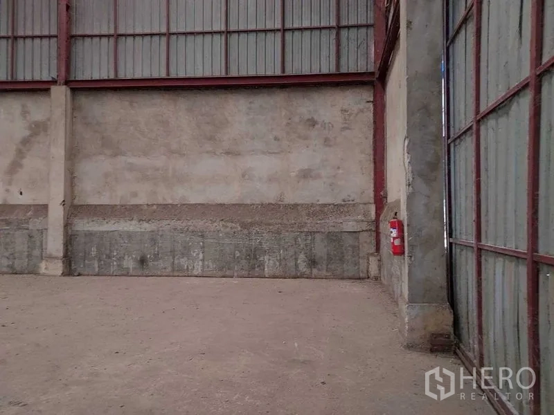 Warehouse for rent in Lat Lum Kaeo, Pathum Thani - Corner of the warehouse showing concrete walls, steel framing, and a mounted fire extinguisher.