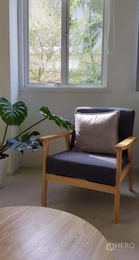 Detached House for rent or sale in Prawet, Bangkok - Cozy reading corner with armchair, cushion and indoor plant by a window.
