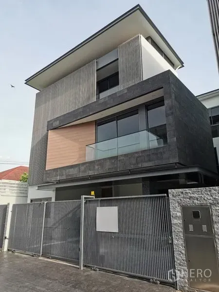 Detached House for sale in Wang Thonglang, Bangkok - Three-storey modern detached house with stone cladding, glass balcony and a gated metal fence in Wang Thonglang.