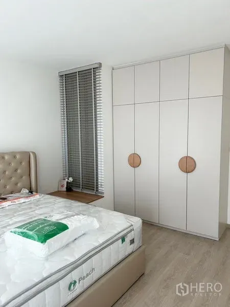 ทาวน์เฮาส์ ให้เช่า - ห้องนอนสว่าง เตียงหุ้มหนัง ตู้เสื้อผ้าสูง และมู่ลี่หน้าต่าง.