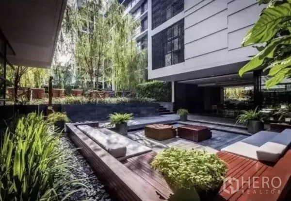 Condominium for rent in Watthana, Bangkok - Landscaped courtyard featuring benches, planters, and lush greenery between condominium buildings.
