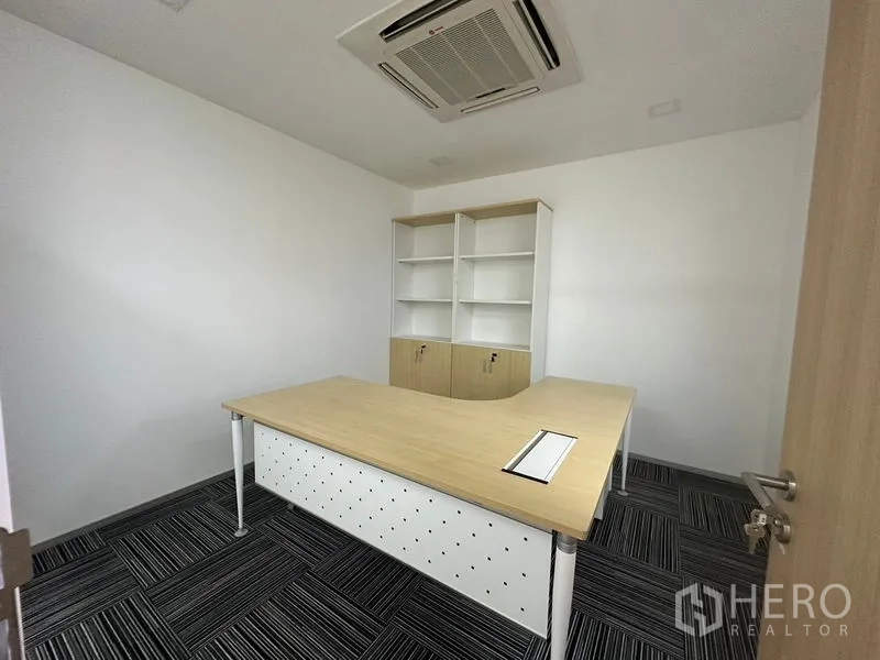 Office Space for rent - Private manager’s office with L-shaped desk, shelving unit, and ceiling cassette air conditioning.