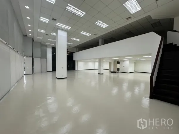 展厅 出租 - 双层挑高展示厅内部，带夹层、立柱与楼梯，顶置照明明亮。