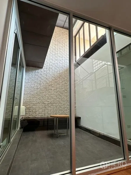 Townhouse for sale in Yan Nawa, Bangkok - Internal courtyard with sliding glass doors, textured brick wall and bench seating