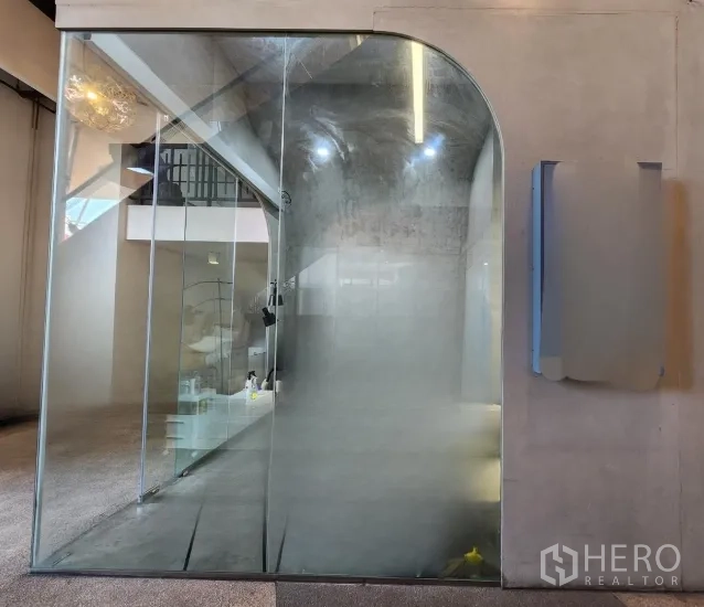 Retail Space for rent in Sathon, Bangkok - Compact retail unit with a floor-to-ceiling arched glass door, polished concrete interior, and ceiling spotlights.