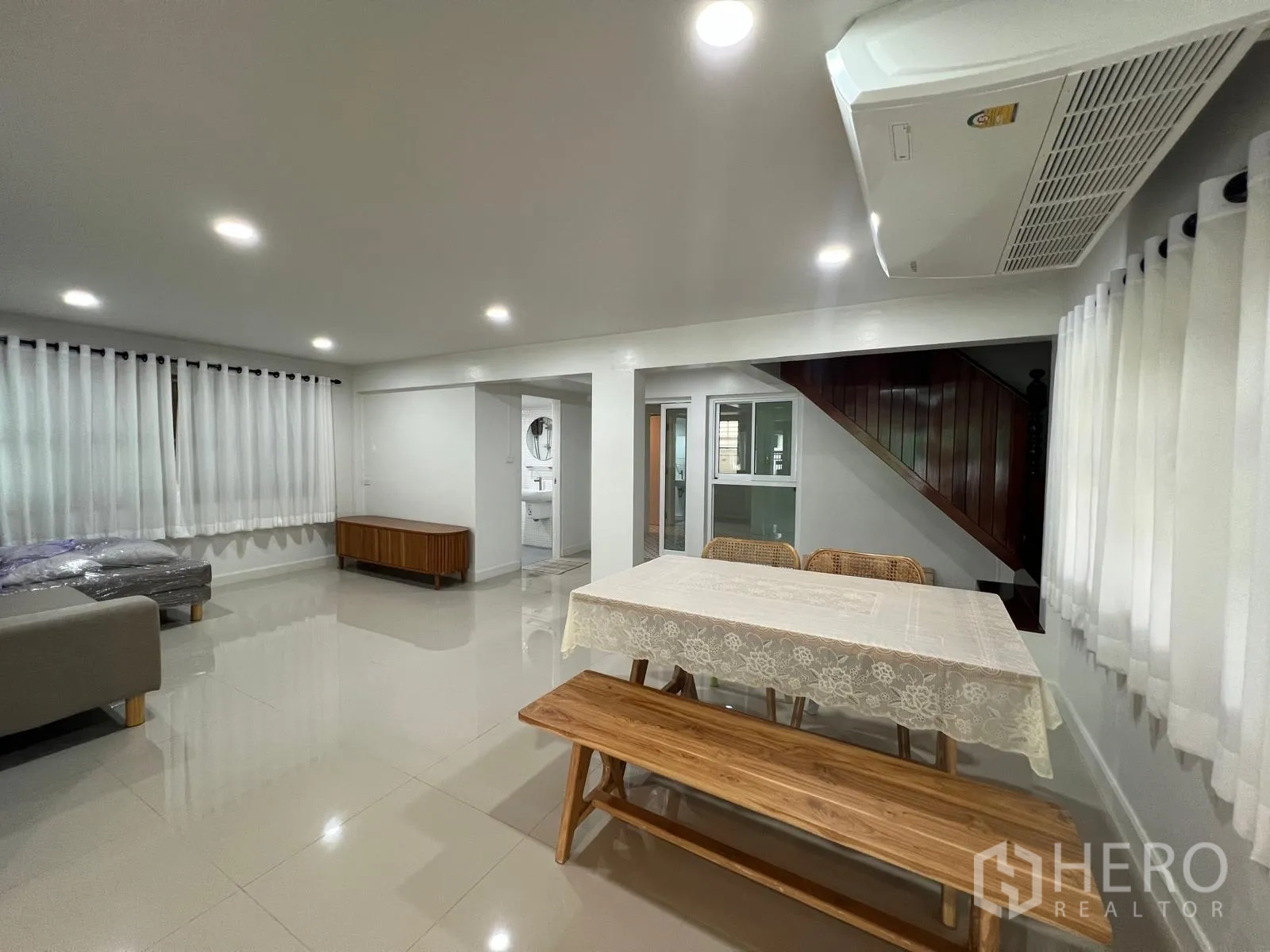 Detached House for rent in Saphan Sung, Bangkok - Dining area with wooden table and bench next to the staircase and bright windows.