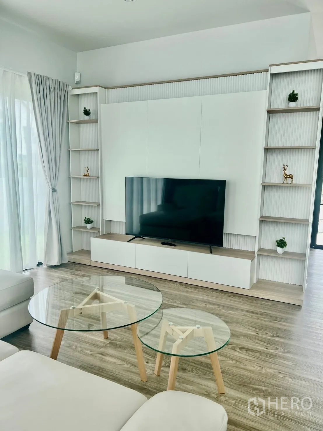 บ้าน ให้เช่าในBang Sao Thong, Samut Prakan - ภาพระยะใกล้ของผนังทีวีบิลท์อิน คู่โต๊ะกลางกระจก บนพื้นลายไม้