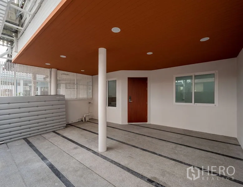 Townhouse for sale in Din Daeng, Bangkok - Covered parking area with warm-toned ceiling and secure gate.