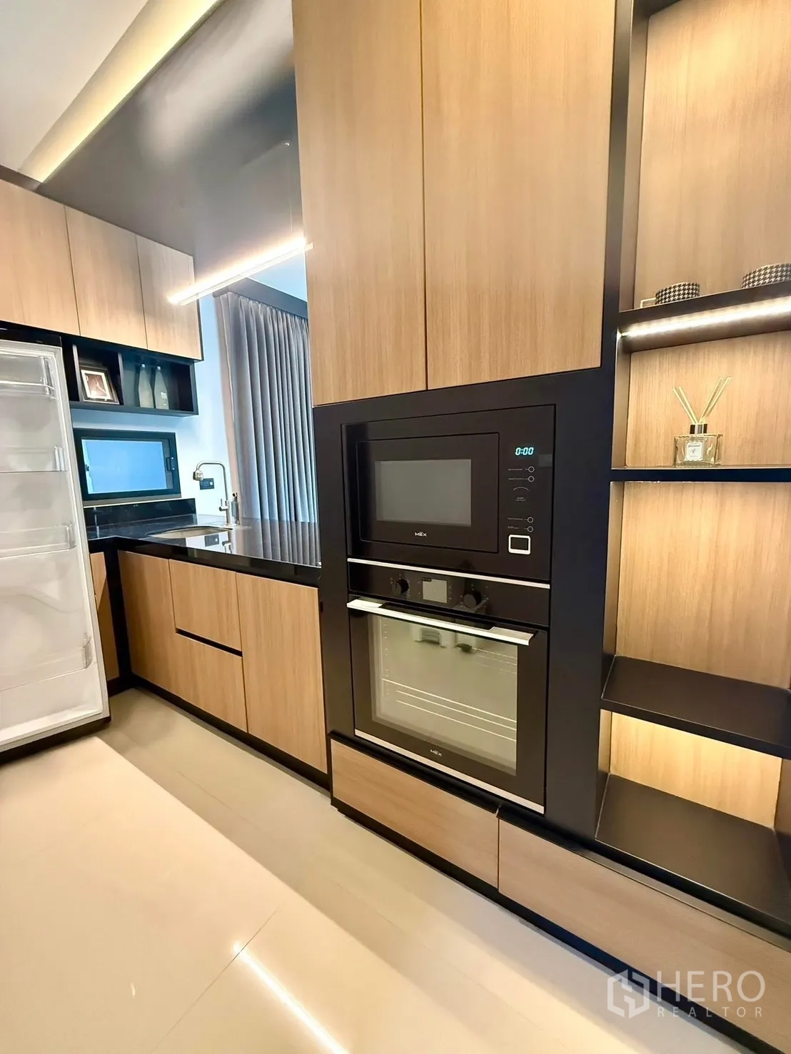 Detached House for rent in Bang Kapi, Bangkok - Modern kitchen with wood built-ins, wall oven, microwave and black stone countertop.