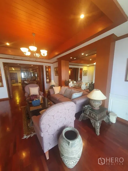 Condominium for rent in Bang Kho Laem, Bangkok - Spacious living room with sofas, chandelier lighting, wood ceiling panels and hardwood flooring.