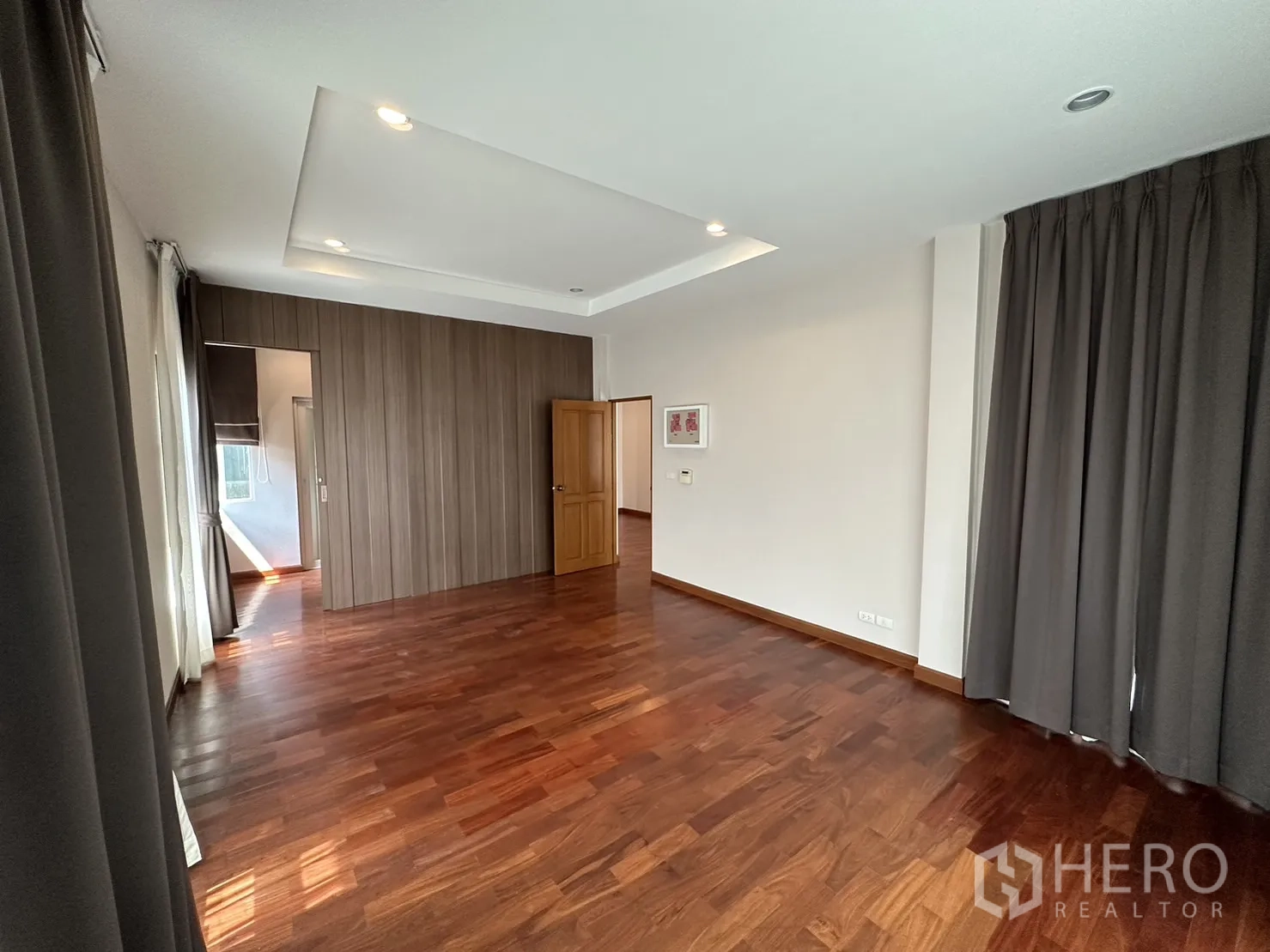 Detached House for rent or sale in Pak Kret, Nonthaburi - Spacious master suite with wood accent wall and doorway to a walk-in closet.