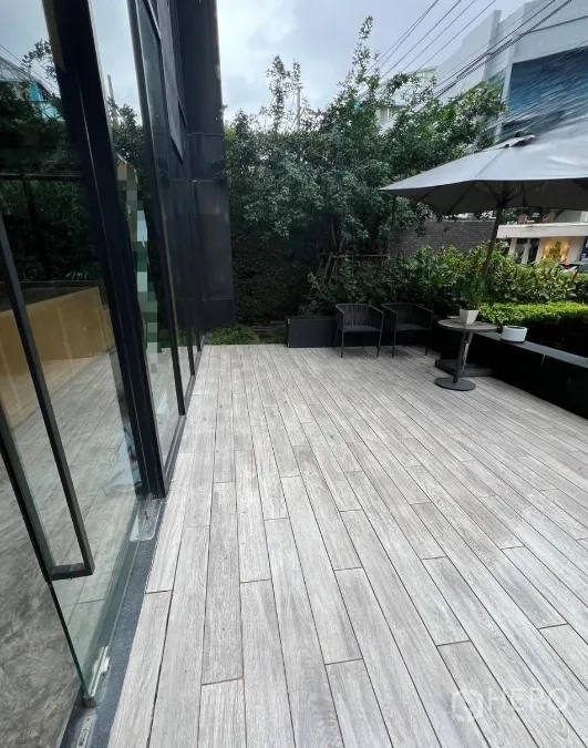 พื้นที่ขายปลีก ให้เช่าในWatthana, Bangkok - เทอเรซภายนอกปูกระเบื้องลายไม้ มีเก้าอี้และร่ม ข้างผนังกระจก