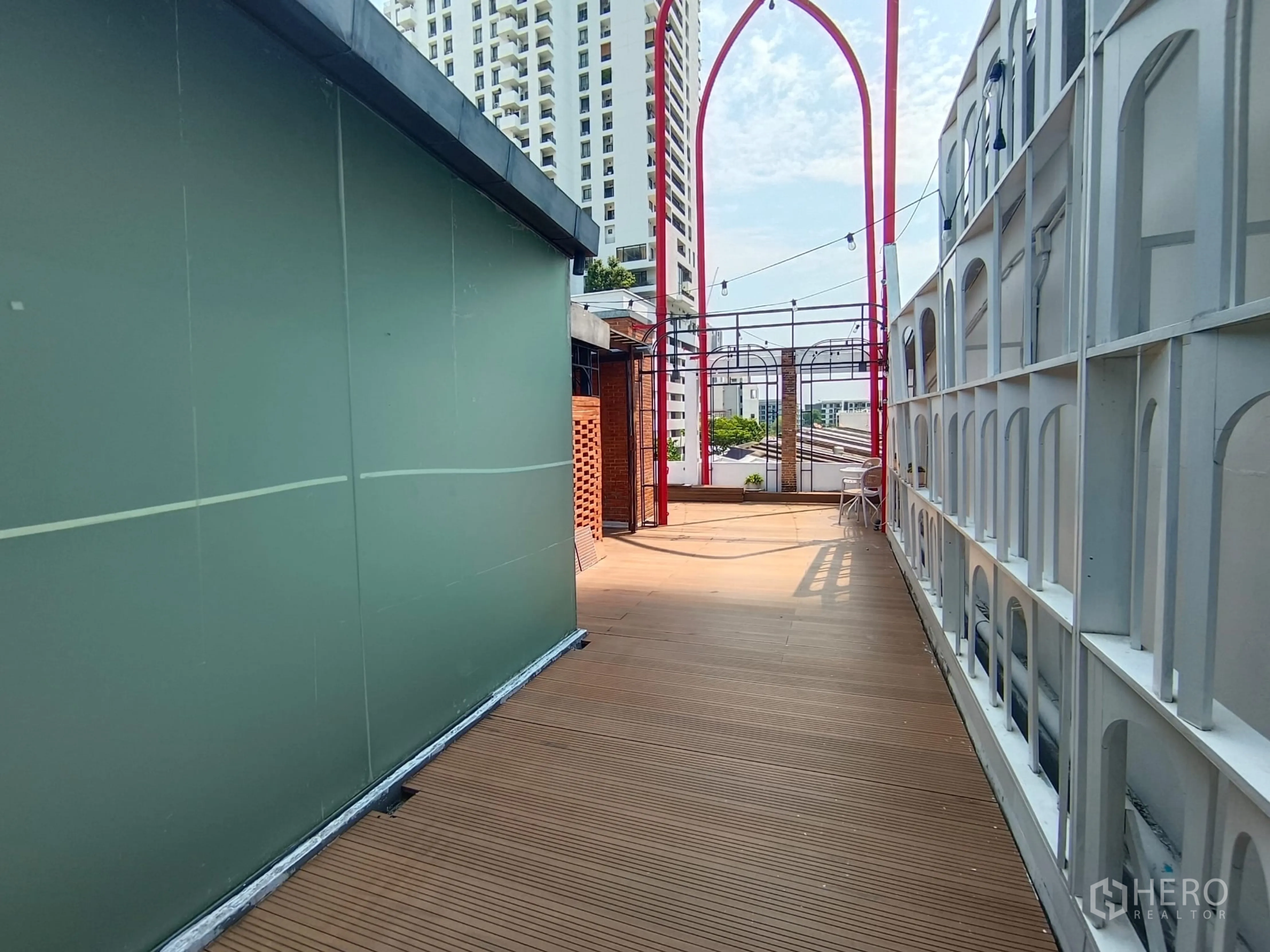 ตึกแถว for rent in Watthana, Bangkok - ดาดฟ้าพื้นไม้พร้อมไฟประดับ มองเห็นอาคารเมืองโดยรอบ.