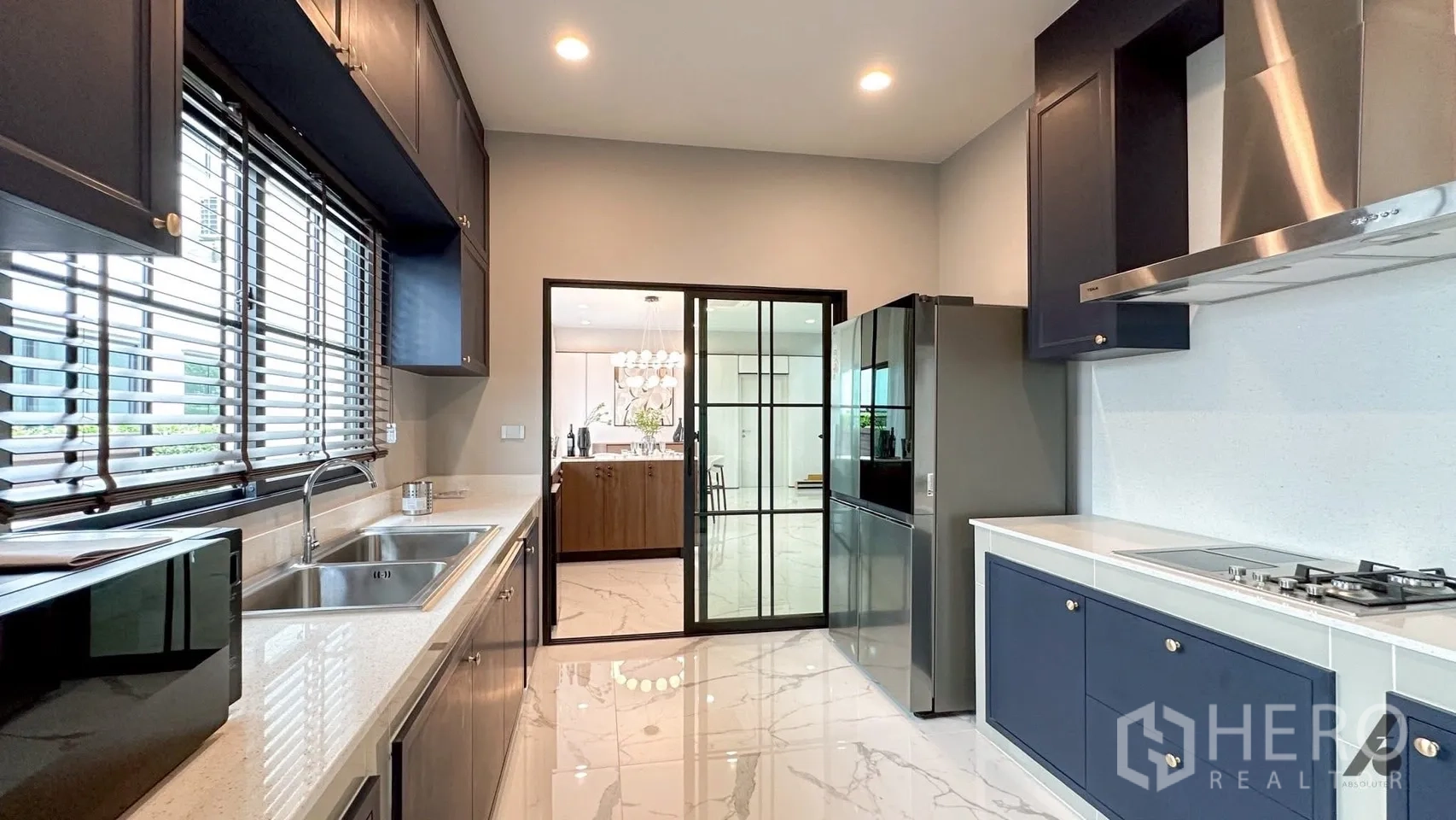 Detached House for rent in Bang Phli, Samut Prakan - Full kitchen view with gas cooktop, stainless hood, double sink, and glass partition to the dining area.