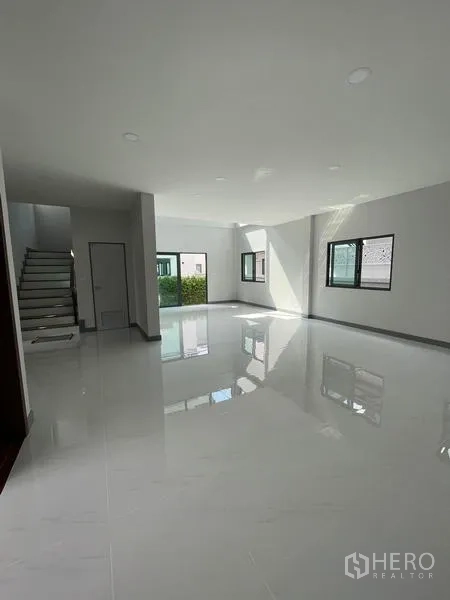 Detached House for rent - Spacious open-plan living area with glossy white floors and stairway.
