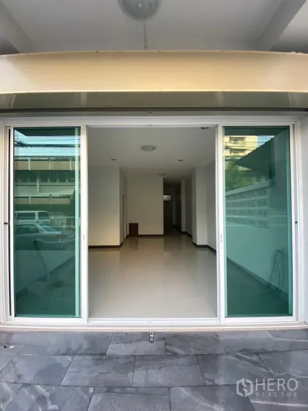 联排别墅 出租在Huai Khwang, Bangkok - 一层入口处的大型绿色玻璃推拉门，通向明亮开放空间