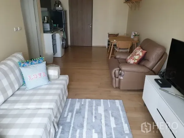 คอนโด ให้เช่าหรือขายในWatthana, Bangkok - โซนนั่งเล่นแบบเปิดโล่ง มีชั้นวางทีวี โซฟา และพื้นที่รับประทานอาหาร มองไปยังครัวและประตูเข้า