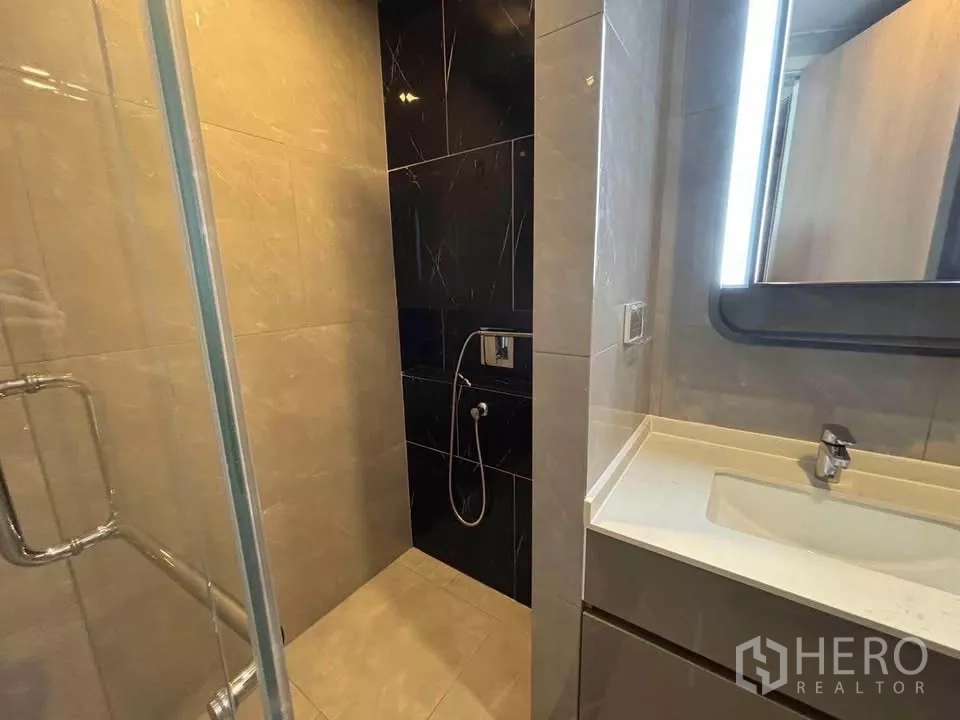 公寓 出租在Huai Khwang, Bangkok - 浴室带玻璃淋浴间、瓷砖墙面与现代洗手台。