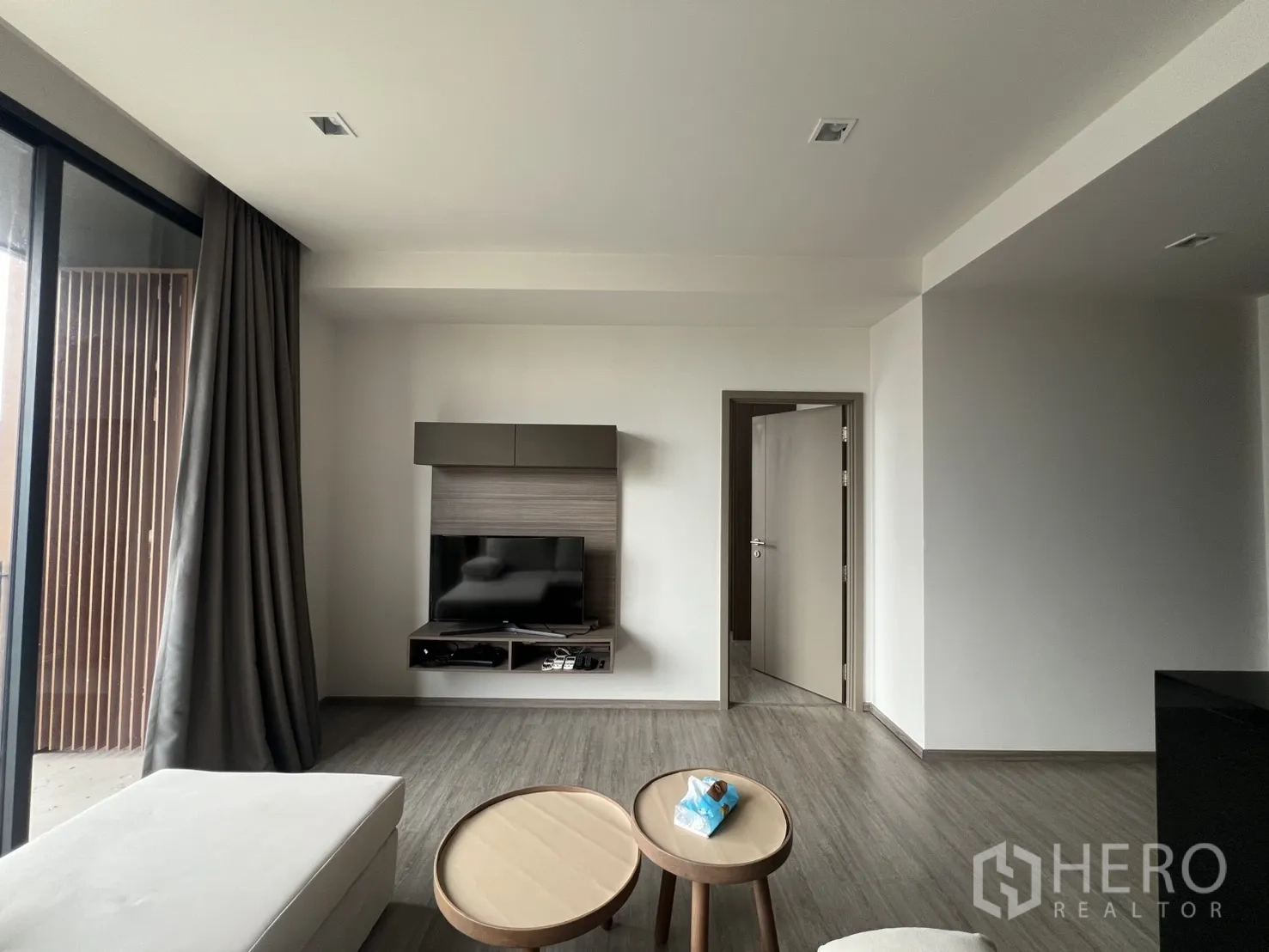 คอนโด for rent in Watthana, Bangkok - มุมนั่งเล่นหันหน้าไปยังผนังทีวีและประตูระเบียงบานเลื่อนพร้อมผ้าม่านสูงจรดเพดาน