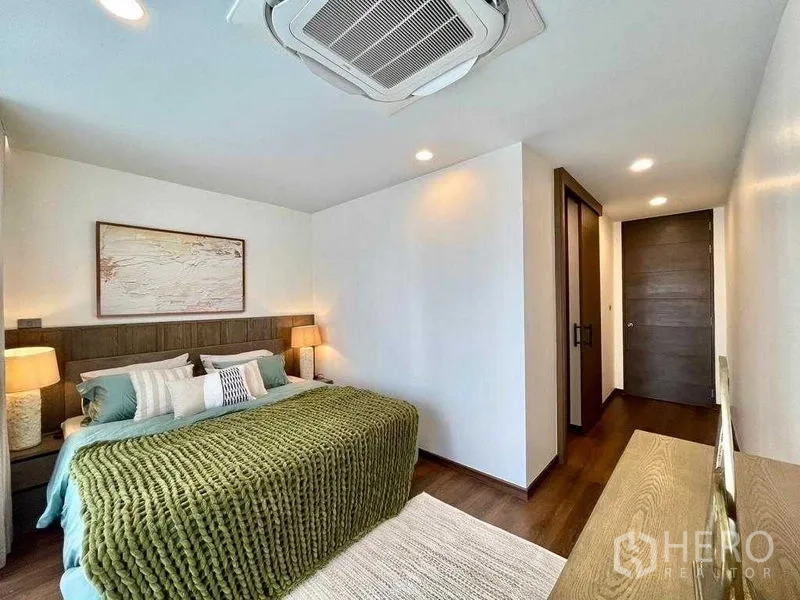 Detached House for rent in Bang Rak, Bangkok - Cozy bedroom with green knit throw, bedside lamps and wood flooring.