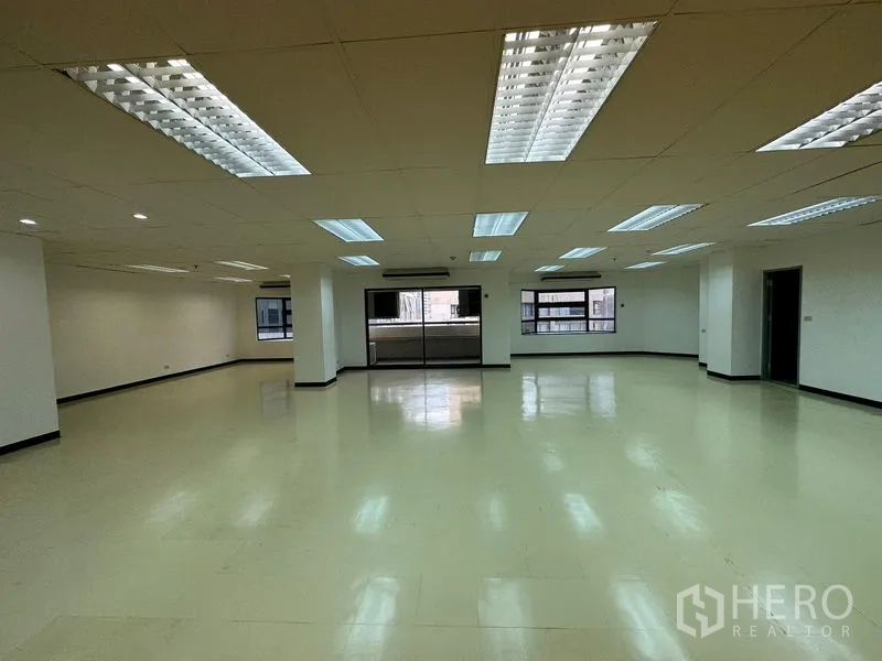 Office Space for rent in Pathum Wan, Bangkok - Large open-plan office with multiple fluorescent light panels, side windows and a central column.