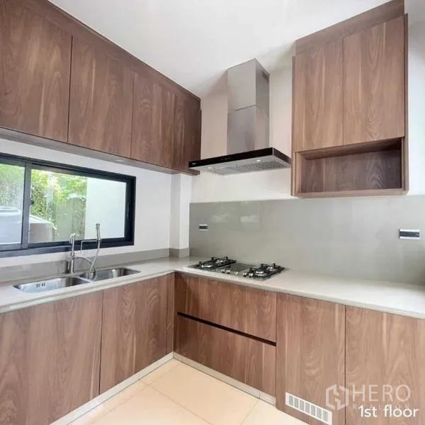 Detached House for rent in Bang Kapi, Bangkok - Modern L-shaped kitchen with gas hob, hood and wood cabinets.
