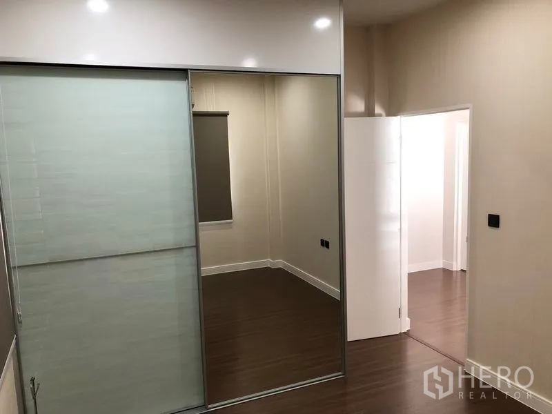Detached House for rent in Bang Kapi, Bangkok - Bedroom with mirrored sliding wardrobe doors and wood flooring.