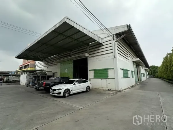 คลังสินค้า ให้เช่าในLat Krabang, Bangkok - ด้านหน้าโกดังมีชายคาโหลดสินค้า ประตูม้วนขนาดใหญ่ พร้อมที่จอดรถและรถบรรทุก