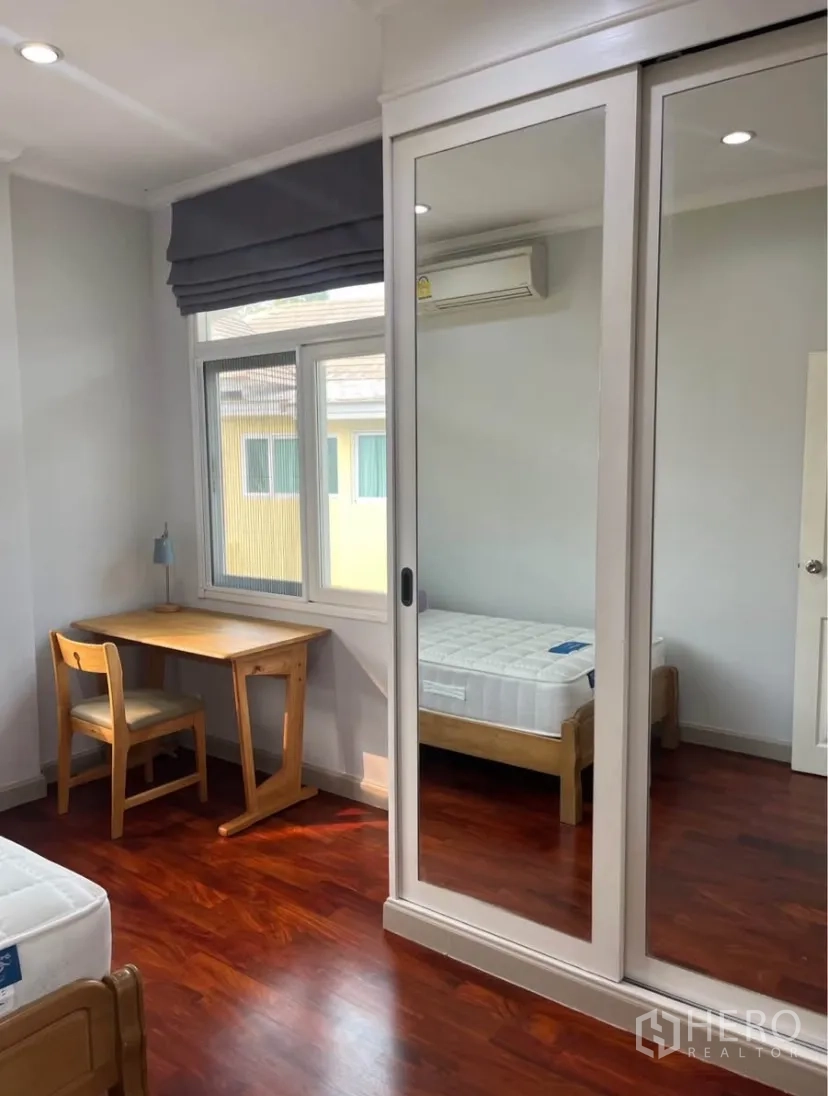 独立式住宅 出租或出售在Lat Phrao, Bangkok - 卧室内镜面推拉衣柜、书桌与空调。