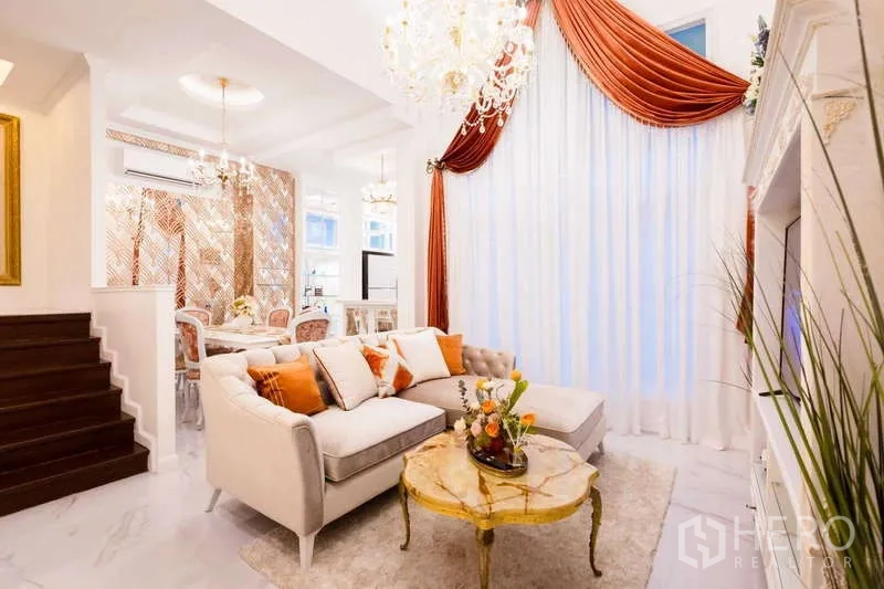 联排别墅 出租在Lat Phrao, Bangkok - 客餐厅一体，水晶吊灯、石材地面和高挑窗帘