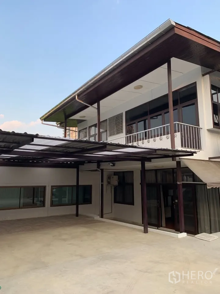 独栋房屋 for rent in Phra Khanong, Bangkok - 两层外观，设阳台与带顶大型车棚，前院铺地。