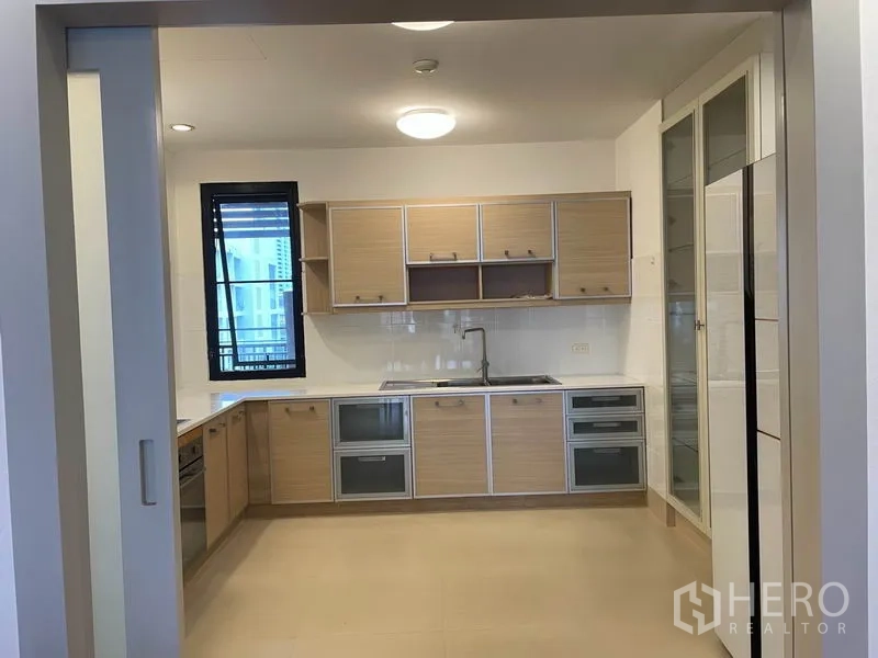 公寓 出租在Watthana, Bangkok - 明亮的独立U型厨房，浅木色橱柜与窗户通风。