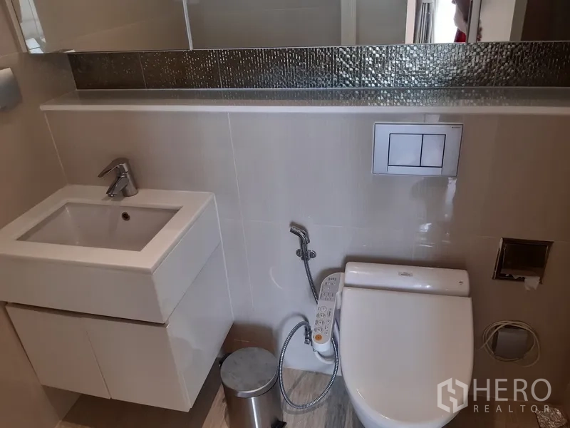 Condominium for rent or sale in Watthana, Bangkok - Modern bathroom with square vanity, bidet toilet and long mirror.