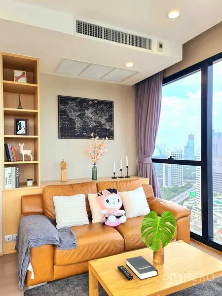 Condominium for rent in Bang Rak, Bangkok - Sofa corner by tall windows with city views and a wooden coffee table.