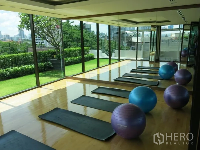 公寓 出租在Ratchathewi, Bangkok - 健身/瑜伽房，镜面墙与木地板，摆放瑜伽垫和健身球，可观花园景。