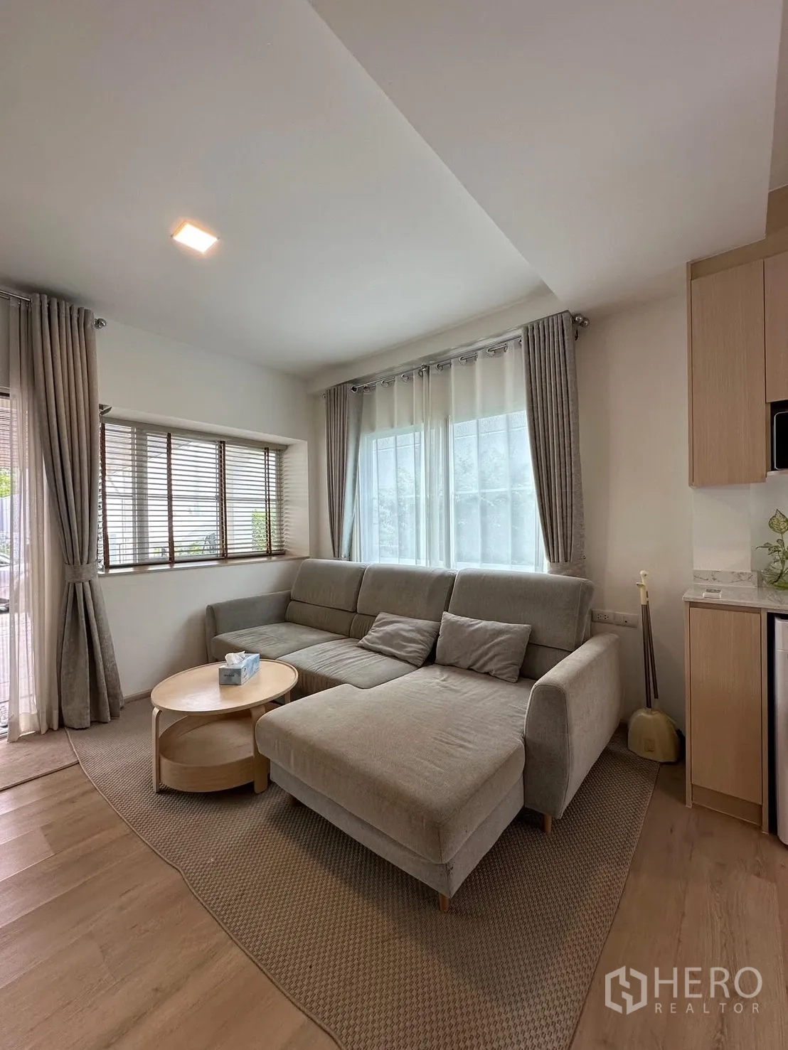 联排别墅 for rent in Prawet, Bangkok - 客厅转角窗旁的L型沙发与窗帘。