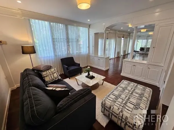 Detached House for rent - Bright living room with large windows, white built-in cabinetry, and a dark sofa on wooden flooring.