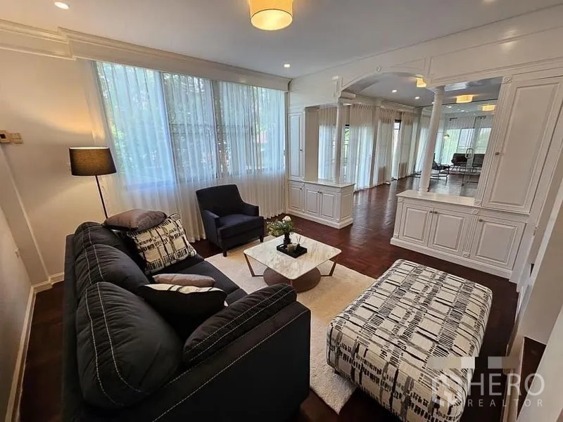 Detached House for rent - Bright living room with large windows, white built-in cabinetry, and a dark sofa on wooden flooring.