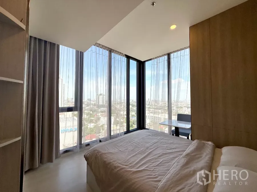 Condominium for sale in Chatuchak, Bangkok - Corner master bedroom with floor-to-ceiling windows and wide Bangkok skyline views.