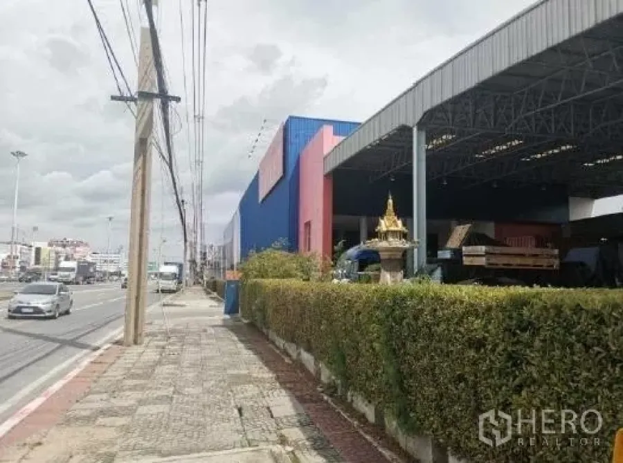 货栈 出租在Khlong Luang, Pathum Thani - 临街仓库外观，带有遮雨装卸区与绿篱围挡。