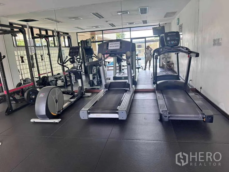 公寓 出租在Sathon, Bangkok - 健身房配跑步机、力量器械与整面镜墙，可眺望泳池区。