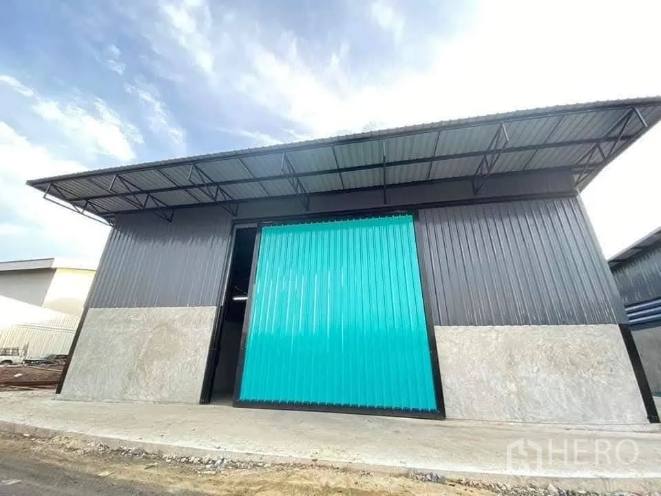 Warehouse for rent in Bang Bua Thong, Nonthaburi - Front exterior of the warehouse with a large sliding metal door and a covered loading eave.
