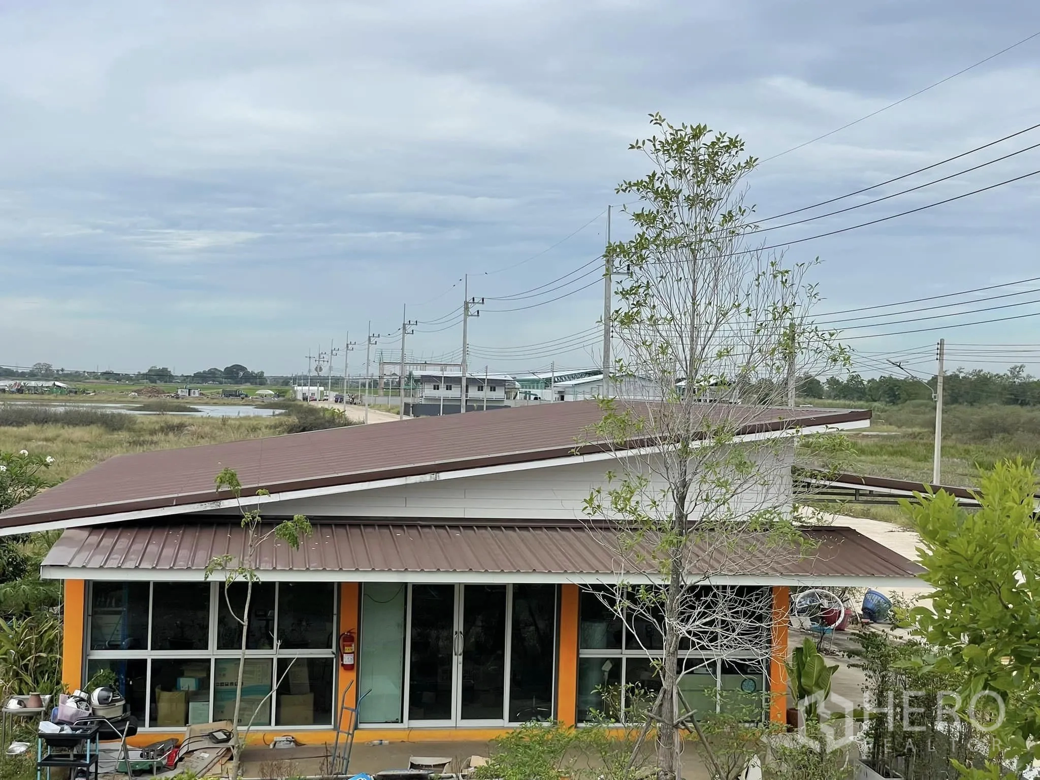 คลังสินค้า ให้เช่าหรือขายในPathum Thani - ภาพมุมสูงของอาคารหลังคาสีน้ำตาลและถนนเข้าโครงการ