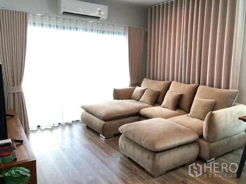 บ้าน ขายในBang Sao Thong, Samut Prakan - ห้องนั่งเล่นอบอุ่น โซฟาหนังกลับสีเบจ ผ้าม่านโปร่งและเครื่องปรับอากาศ