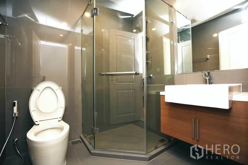 คอนโด ให้เช่าหรือขายในBang Rak, Bangkok - ห้องน้ำสมัยใหม่ พร้อมตู้กระจกอาบน้ำมุม เคาน์เตอร์ลอย และกระเบื้องสีเทา